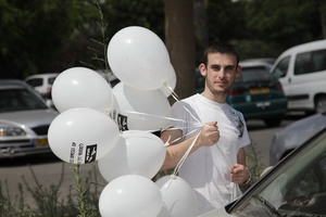 Volunteer hanging balloons on handles of cars